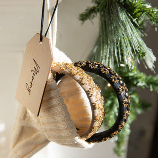 Three decorative headbands on a white surface with a green wreath in the background.