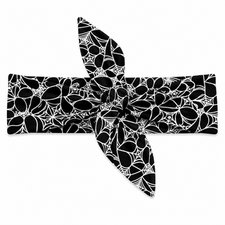 A black fabric headband with a white spiderweb and spider-themed floral pattern, styled in a knot on a solid white background.